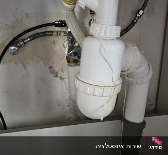 צנרת מתחת לכיור עם סימני נזילה